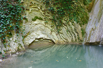 Marvellous lake with stagnant water among the rocks covered with ivy and moss