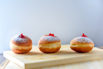 Close up view of tasty Jelly Doughnuts with jam on wood background. Hanukkah celebration concept.
