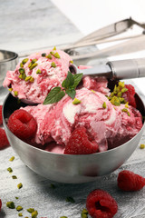 Raspberry ice cream scoop with chopped nuts and white chocolate on a rustic background