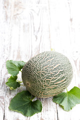 Honeydew melon with sprig on white wooden table