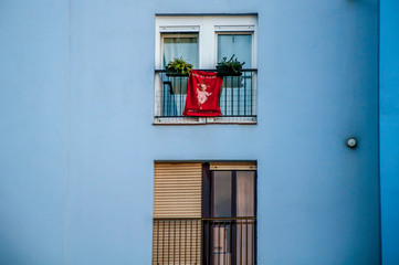 A blue house with french balcony and a flag with the text Feliz Navidad hanging.
