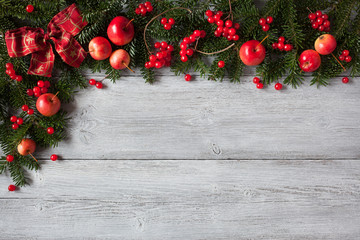 Fototapeta na wymiar Christmas wooden background with fir branches, red apples and berries