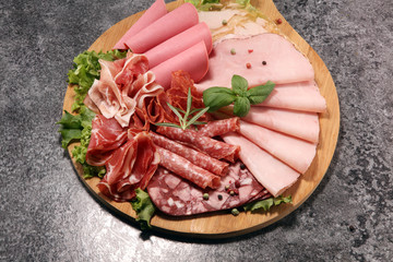 Food tray with delicious salami, pieces of sliced ham, sausage and salad. Meat platter with selection.