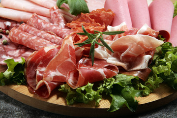 Food tray with delicious salami, pieces of sliced ham, sausage and salad. Meat platter with selection.