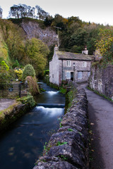Fototapeta na wymiar Quaint cottage in the peak district with a running river and rock wall