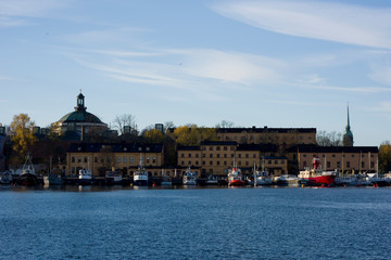 Obraz premium A sunny autumn morning view in Stockholm harbour, Skeppsholmen island with boats an landmarks