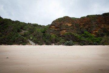 Cliff and rocky beach on a beautiful cloudy day in the middle of Great Ocean Road, Victoria, South Australia.