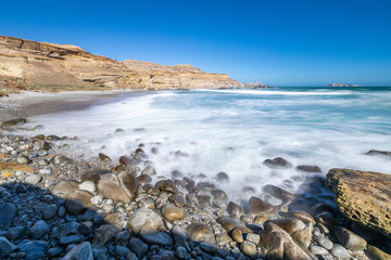 Chorrillos Beach white waters crashing with the coastline rocks during a long exposure shot at Chile with the Atacama Desert sands ending on the Pacific Ocean waters, maybe the best beaches in Chile
