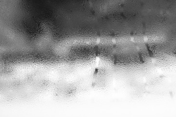 Condensate on the glass is black, moist texture of water, steam, rain outside the window. Natural background. Abstract wallpaper