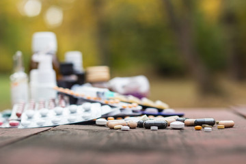 Medicines on wooden table, nature bokeh background