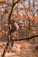 Brown plush mouse sitting on the tree branch in spring park.