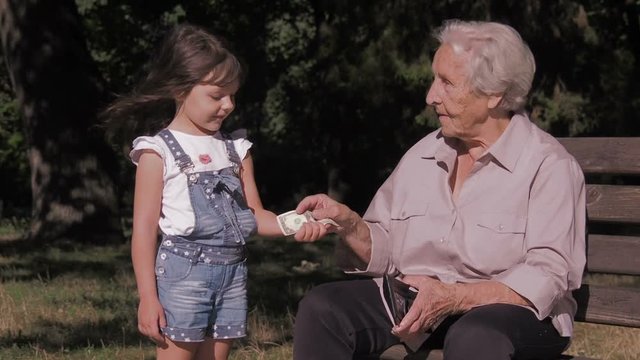 A child asks an elderly woman for money. Granddaughter asks grandmother for money.