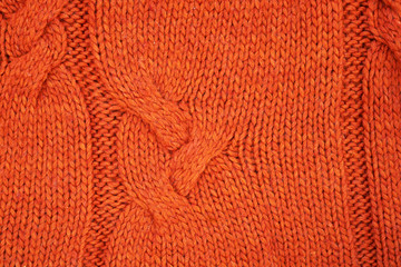 Red knitted texture with a relief pattern. Handmade Knitwear. Background, abstract.