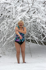 Aged woman in swimwear is rubbing herself with snow.