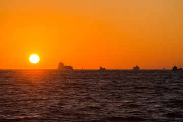 Fototapeta na wymiar 日の出の太陽と水平線と渡る船たち