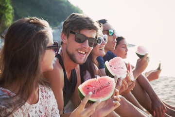 Friends eating watermelon on beach