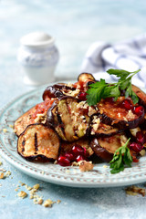 Grilled eggplants in tomato sauce with walnuts and pomegranate seeds.