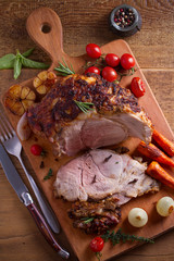 Baked ham with vegetables, rosemary and thyme on chopping board. overhead, vertical