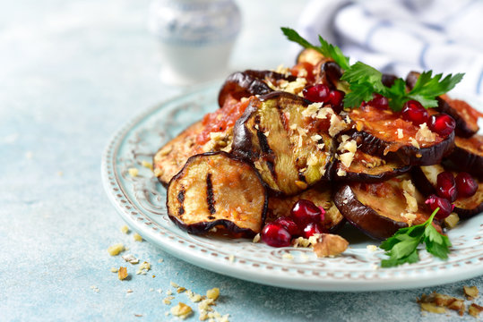 Grilled eggplants in tomato sauce with walnuts and pomegranate seeds.