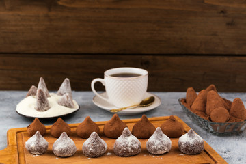 Chocolate truffles covered with powdered sugar and cocoa powder, wooden background.