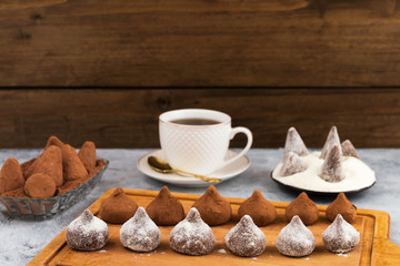 Preparation of chocolate truffles with sprinkling of cocoa powder and powdered sugar.