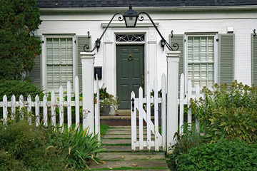front door of small white brick house with picket fence