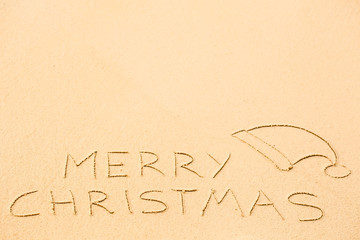 Merry Christmas inscription on wet yellow beach sand