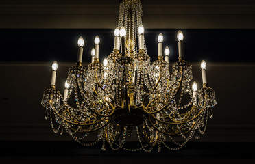 beautiful vintage style chandelier lit up hanging from ceiling.