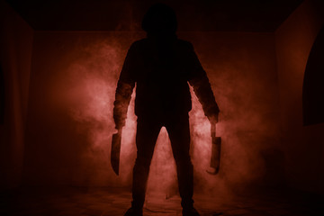 A dangerous hooded man standing in the dark and holding a knife. Face can not be seen. Committing a...