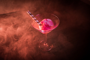 Martini glass filled with colorful fruit ice cream on dark background with toned light and fog