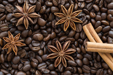 Anise stars and cinnamon sticks on coffee beans background.