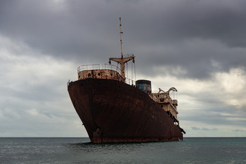 rusty cruiser in the ocean under a grim leaden sky