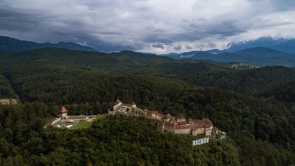 Fototapeta na wymiar Aerial landscape of Rasnov Castle, with Bucegi massif in Carpathian Mountains on a sunny day.