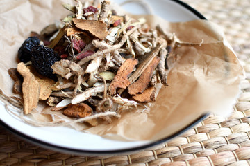 Chinese traditional medicine script. Herbal tea with jujubes, goji berries, gingseng roots and others on parchment paper on neutral background.