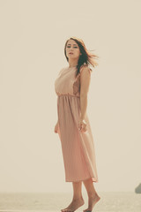Woman wearing long light pink dress on jetty