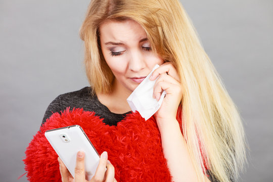 Sad heartbroken woman looking at her phone