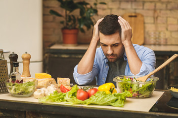 People, tiredness and overwork concept. Sad unhappy tired man coocking in the kitchen. Chef in stress.