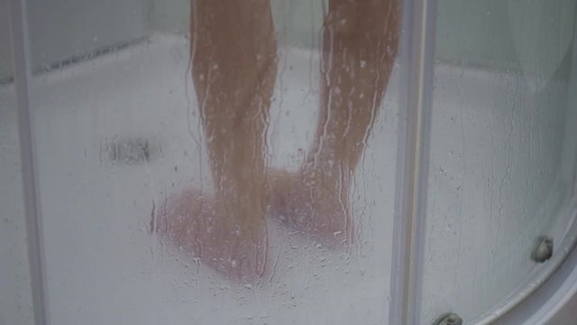 Feet of a child in the shower. Young girl bathing under a shower at home
