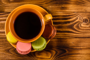 Cup of coffee and french macaroons on wooden table. Top view