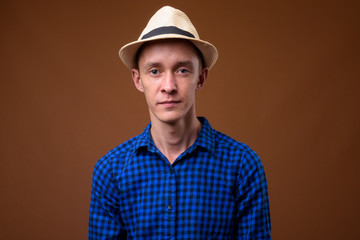 Studio shot of young tourist man against brown background