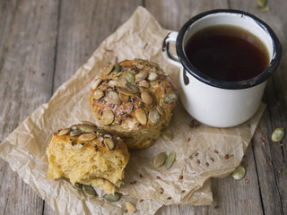 Homemade Autumn Pumpkin Muffins with cheese, paprika and sea salt ready to eat with a metal mug of tea on wooden background. Copy space, close up, selective focus