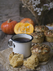 Homemade Autumn Pumpkin Muffins with cheese, paprika and sea salt ready to eat with a metal mug of tea on wooden background. Copy space, close up, selective focus
