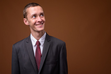 Studio shot of young businessman against brown background