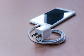 Closeup Shot of Charger Adapter with Smartphone on Brown Background
