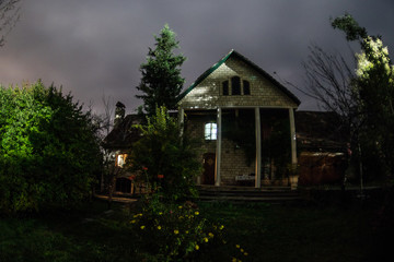 Mountain night landscape of building at forest at night with moon or vintage country house at night with clouds and stars. Summer night.
