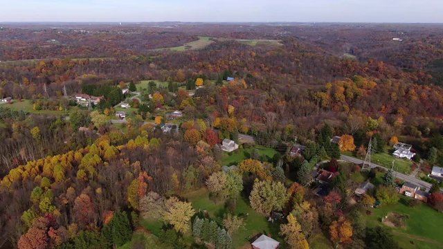 A forward moving aerial establishing shot of the Pennsylvania landscape in late Autumn. Powerlines and colorful Fall foliage in the distance. Pittsburgh suburbs.  	