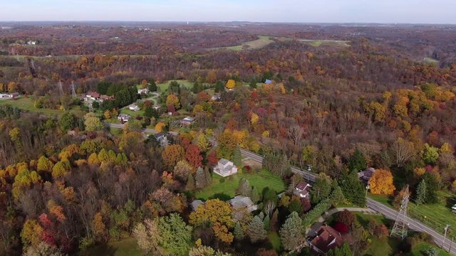 An orbiting aerial establishing shot of the Pennsylvania landscape in late Autumn. Powerlines and colorful Fall foliage in the distance. Pittsburgh suburbs.  	