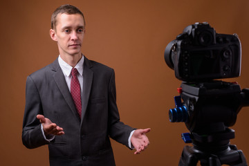 Studio shot of young businessman against brown background