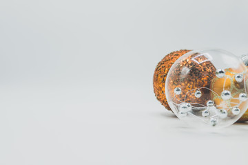 Transparent christmas ball with silver spheres and orange and golden baubles.