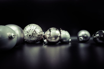 Elegant greyscale Christmas baubles on black.